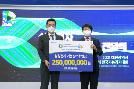 지난 5일 대전에 위치한 엑스포시민광장에서 열린 '제56회 전국기능경기대회' 개회식에서 장동섭 삼성전자 삼성기능올림픽 사무국장(왼쪽)이 안경덕 고용노동부 장관(오른쪽)에게 대회 후원금을 전달하고 있다. <삼성전자 제공>